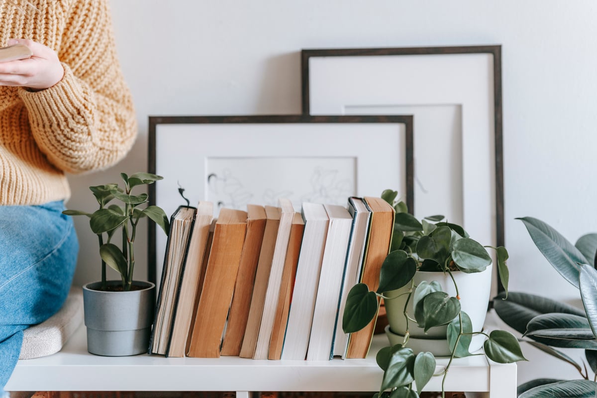 Crop woman sitting near books and plant